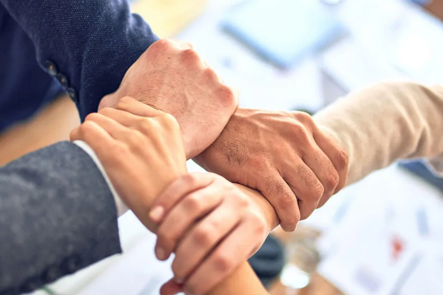 Several hands gripping each other’s wrists in a show of trust
