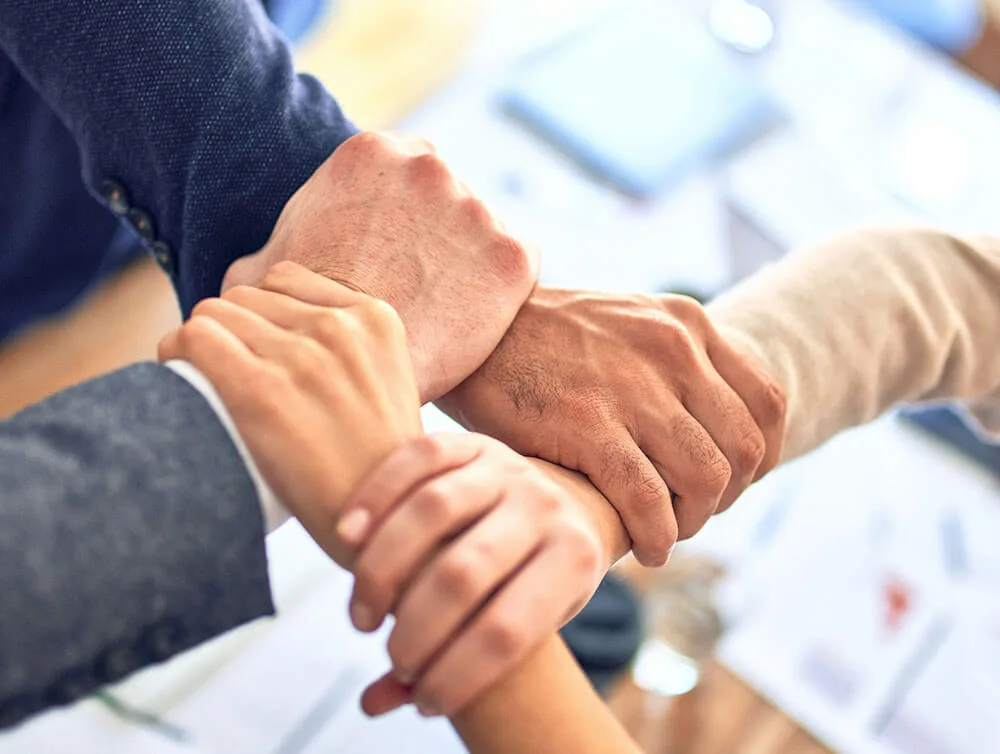 Several hands gripping each other’s wrists in a show of trust