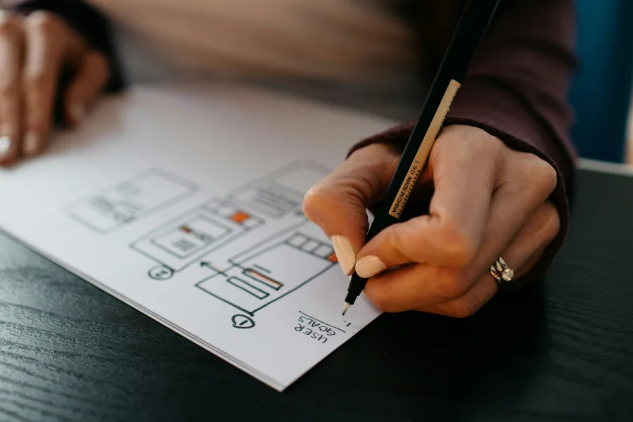 A hand sketching website wireframes with a pen
