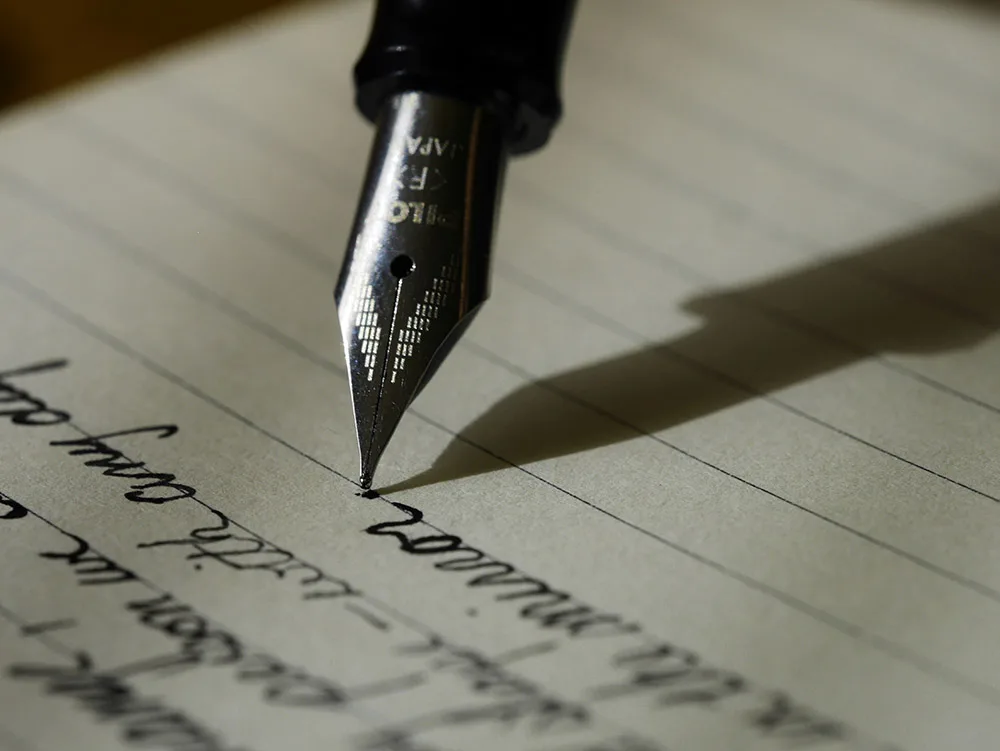 Fountain pen writing on lined paper, representing website copywriting